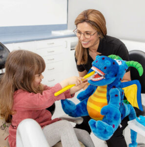 child with toy, toothrush and dentist